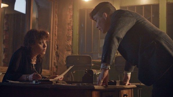 An image of Thomas Shelby standing over Polly Gray (From Peaky Blinders) as she sits in a dim office